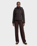 A person stands facing forward against a plain light gray background, wearing the Rudsak MELISSA - 8124824 Espresso/Black women’s lightweight down puffer. She pairs it with brown wide-leg pants and brown sneakers.
