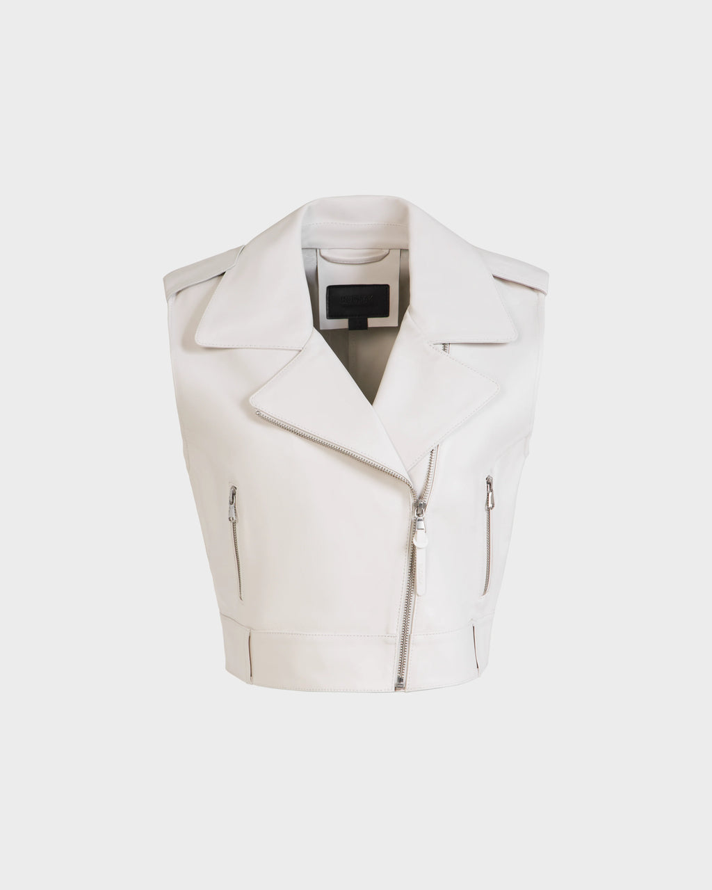 The Rudsak BETTY - 8125000 Optic White is a sleeveless cropped leather vest featuring wide lapels, an asymmetrical front zipper, and two zippered side pockets, shown on a plain white background.