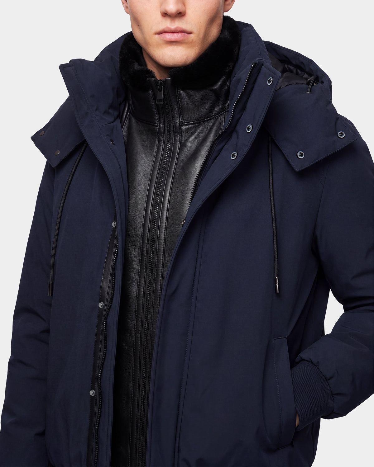 A man wearing the WILL - 6126561 Navy down winter coat by Rudsak over a black zip-up jacket, with his hand in the pocket and only the lower part of his face visible.