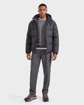 A man wearing the Rudsak STERLING W - 6126760 Heather Charcoal puffer jacket over a gray sweater and shirt, paired with gray pants and brown sneakers, stands facing forward against a plain white background.