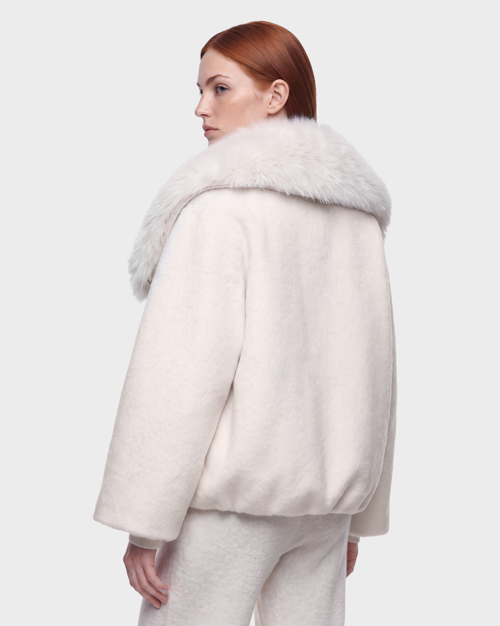 A person with straight red hair models the Rudsak ZARIA - 8126999 Vanilla white winter puffer coat with a faux-fur collar and matching pants, standing against a light gray background and looking over their shoulder.