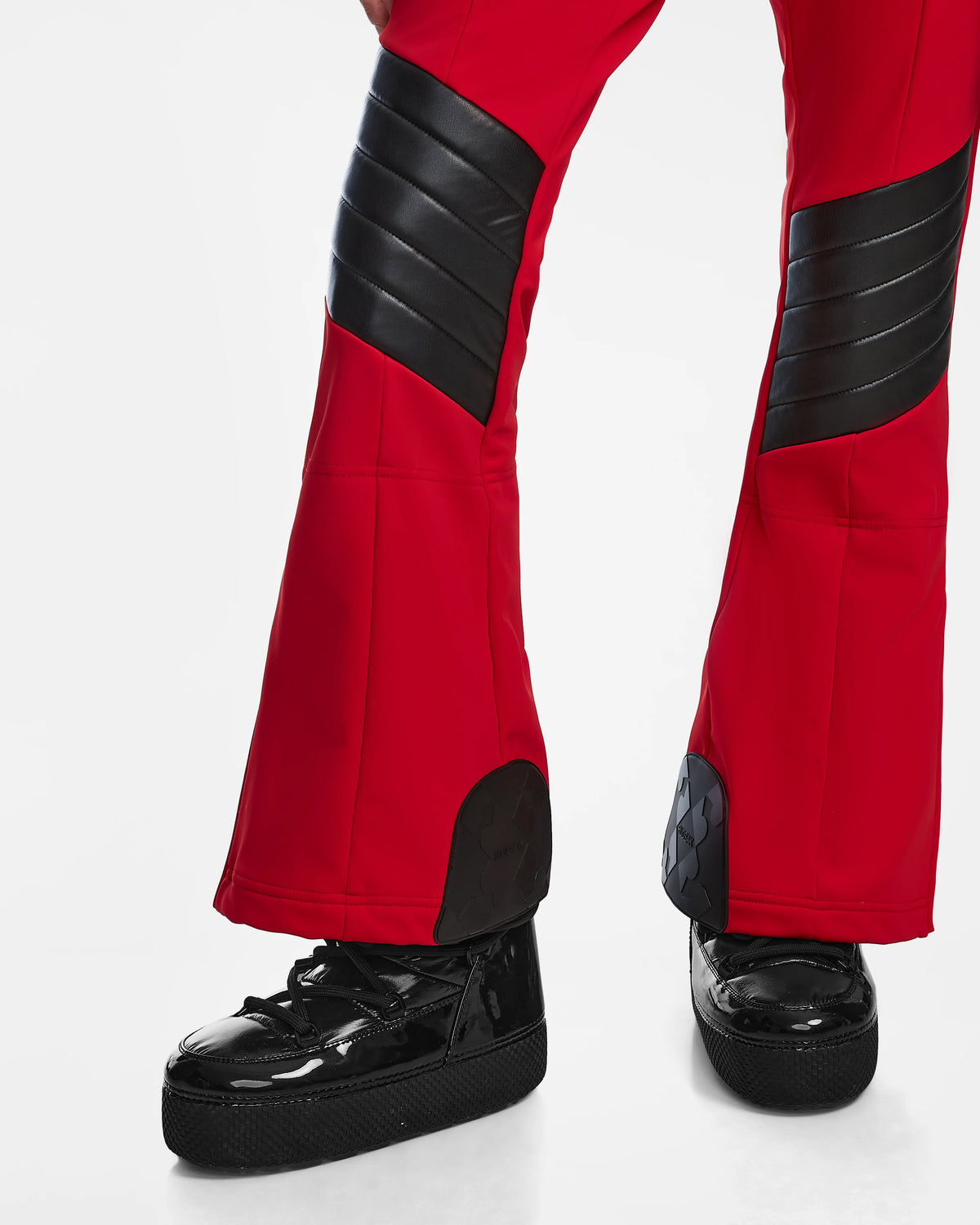 A person models Rudsaks ARLEY - 8124717 Flame Red pants with black padded panels and shiny black platform shoes, standing against a white background with only the legs and feet visible.