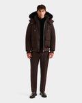 A man faces forward against a white background, wearing the Rudsak JEROME - 6125514 Espresso men’s down bomber jacket with large front pockets, dark trousers, a black turtleneck, and black shoes.