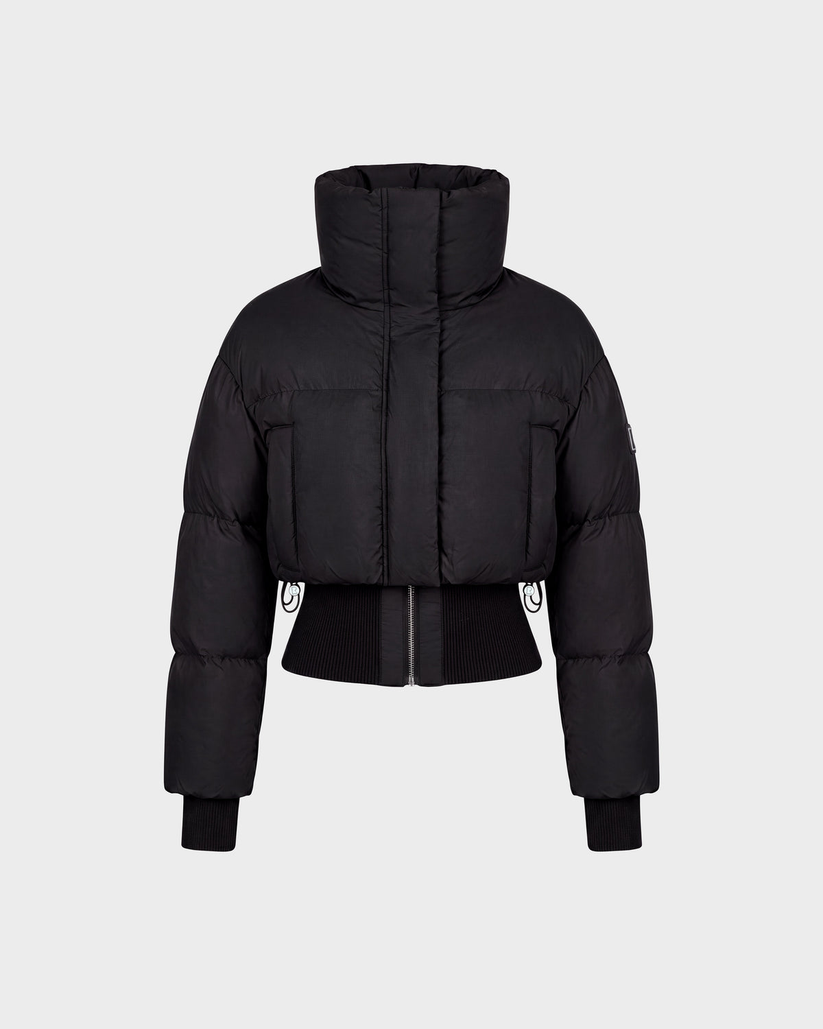 The Rudsak DONYA - 8126516 Black is a black cropped puffer jacket featuring a high collar, long sleeves, ribbed cuffs, and a front zipper, shown against a plain light gray background. Now available for pre-order; expected to ship by September 15th.
