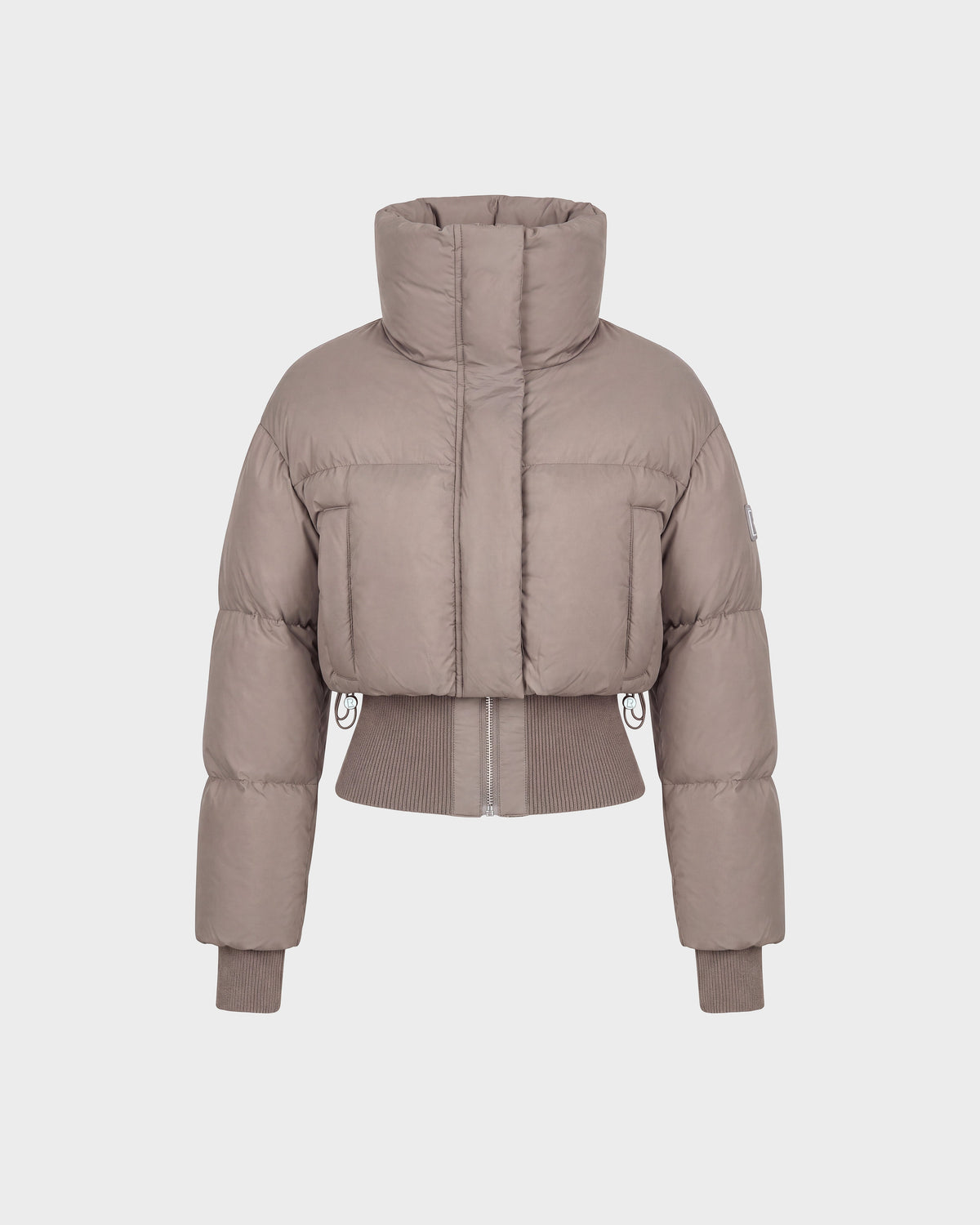 The Rudsak DONYA - 8126516 Cement is a taupe-colored, cropped women’s down puffer jacket made with RDS-certified down, featuring a high collar along with ribbed cuffs and hem, shown against a plain white background.