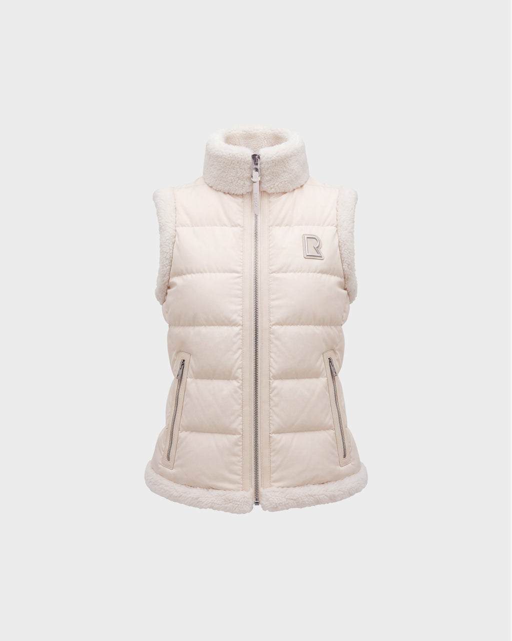 Introducing the HALI - 8126771 Vanilla by Rudsak: a cream-colored, sleeveless puffer vest featuring down insulation and sherpa lining on the collar, armholes, and hem. This vest includes a full zipper, two front zip pockets, and is finished with Rudsak’s signature small embroidered “R” logo on the left chest.