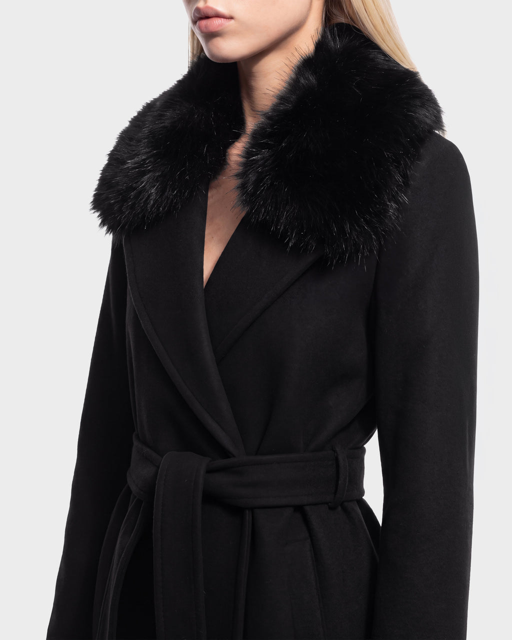 A woman is shown from the shoulders to mid-thigh wearing the Rudsak MEL - 8126525 Black coat, which features a wide faux fur collar and a belted waist, set against a plain light background. This stylish coat is available for pre-order now and is expected to ship by September 15th.