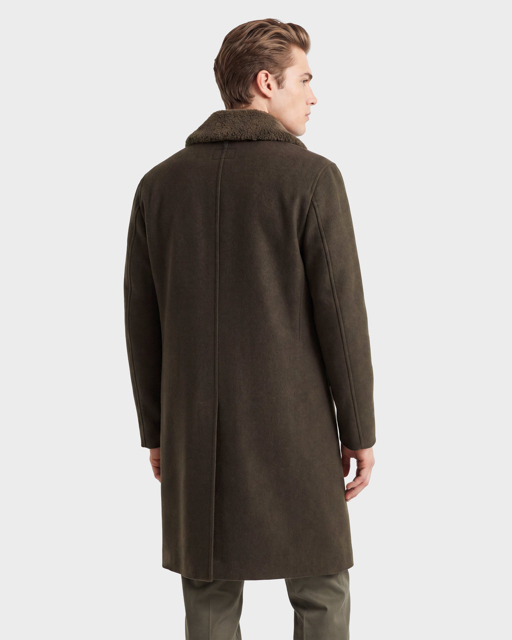 A man with light brown hair, wearing the Rudsak NICO - 6126717 Olive wool blend overcoat with a fur collar, stands facing away against a plain white background—a perfect example of transitional layering.