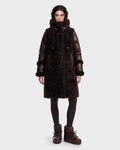 A person stands facing forward wearing the Rudsak SHELLEY - 8126729 Espresso, a dark brown sherpa-textured winter coat with a high collar and matching hood, paired with leggings and boots, in front of a plain white background.