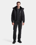 A man stands facing forward wearing the Rudsak WILL - 6126561 Black jacket with a fur collar, styled with a dark cable-knit sweater, black jeans, and black shoes against a plain white background.