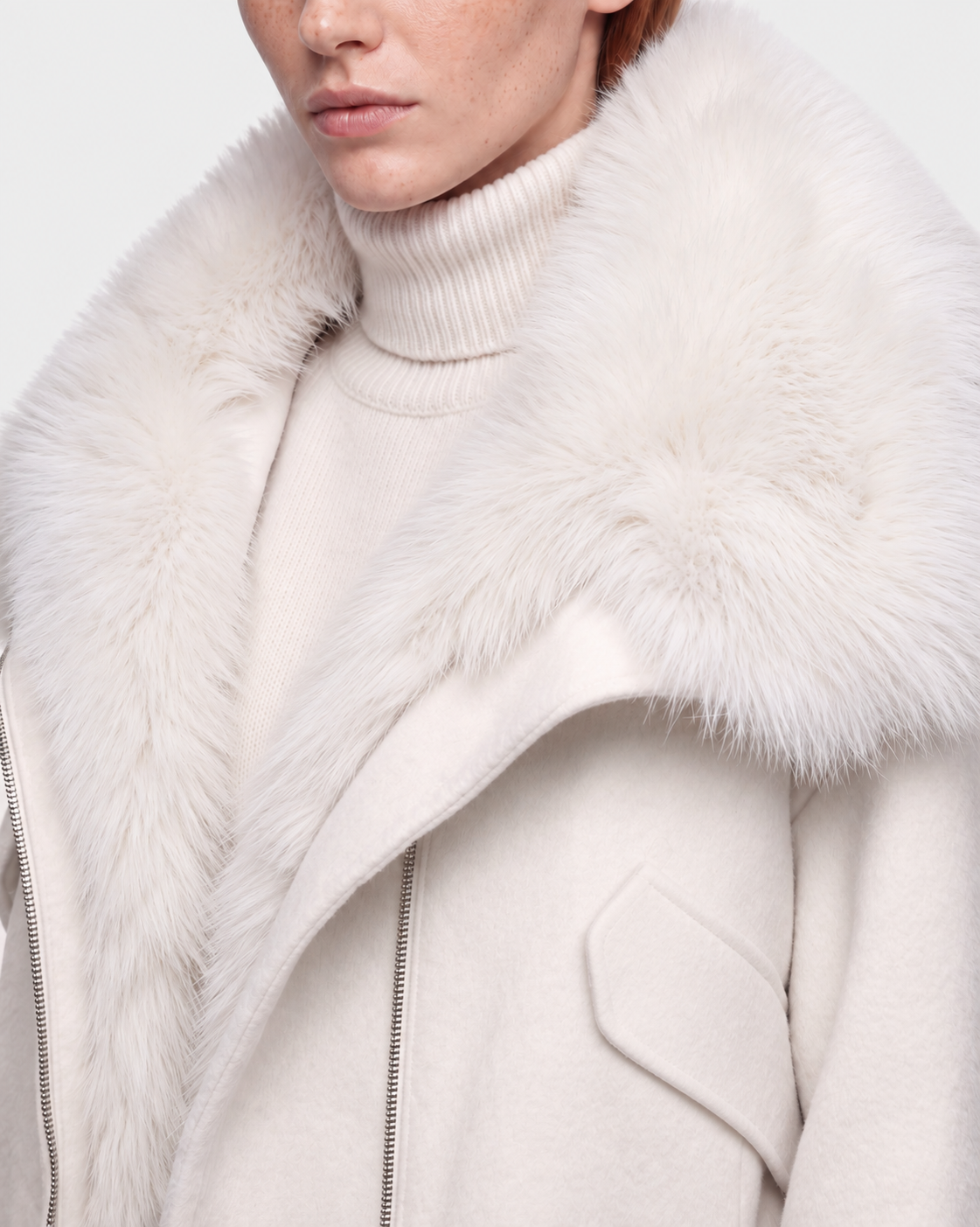 A person wears the Rudsak ZARIA - 8126999 Vanilla coat, featuring a cream hue, wide faux-fur collar, and matching turtleneck; only the lower face and upper torso are visible.