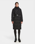 A person faces forward wearing the Rudsak DALSA - 8124691 Black women’s long down puffer winter coat with a hood, paired with black leggings and ankle boots against a plain white background.