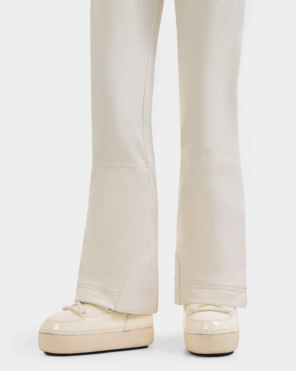 A close-up of a person wearing Rudsak's CARMEN P - 8125707 Vanilla Deja vu pants and matching thick-soled sneakers, showing only lower legs and feet. Available for pre-order; shipping by November 30th.