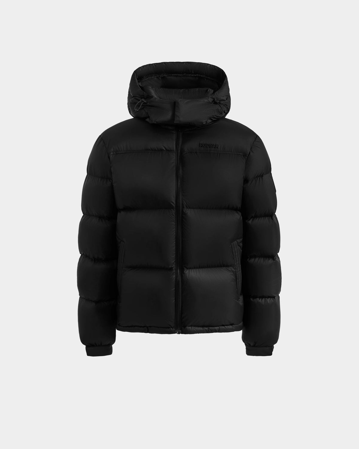 The Rudsak STEFANO - 6125574 Black men’s quilted down puffer jacket features a hood, front zipper, and insulated sections. Displayed on a light gray background, it’s ideal winter outerwear with RDS-certified down for superior warmth.