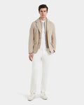 A man faces forward against a white background, showcasing Rudsaks KEITH - 6125045 Almond blazer-style jacket over a white shirt, off-white pants, and white sneakers.