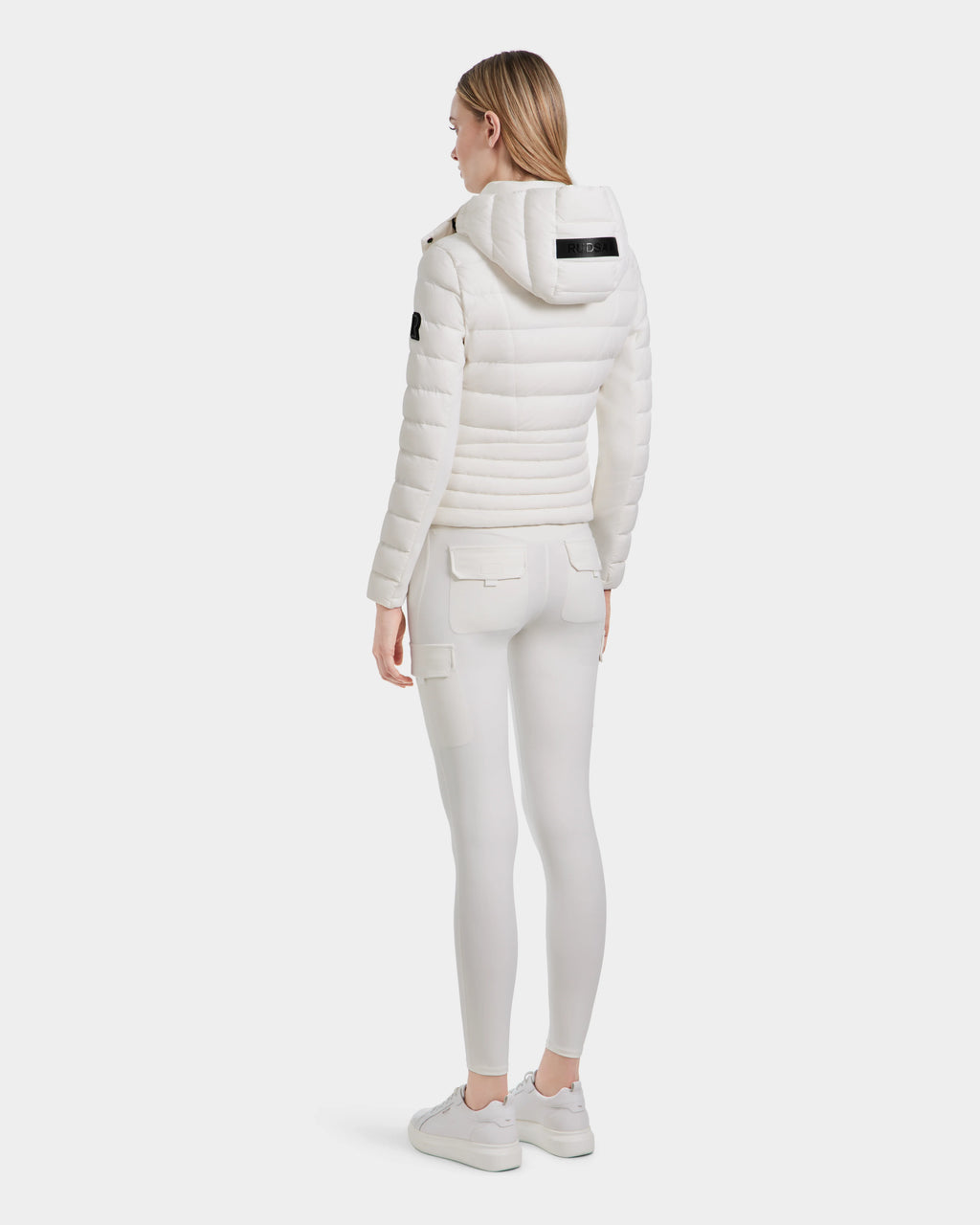 A woman in MELISSA - 8124031 Cotton White pants by Rudsak and a women’s lightweight down puffer, crafted from RDS certified down.