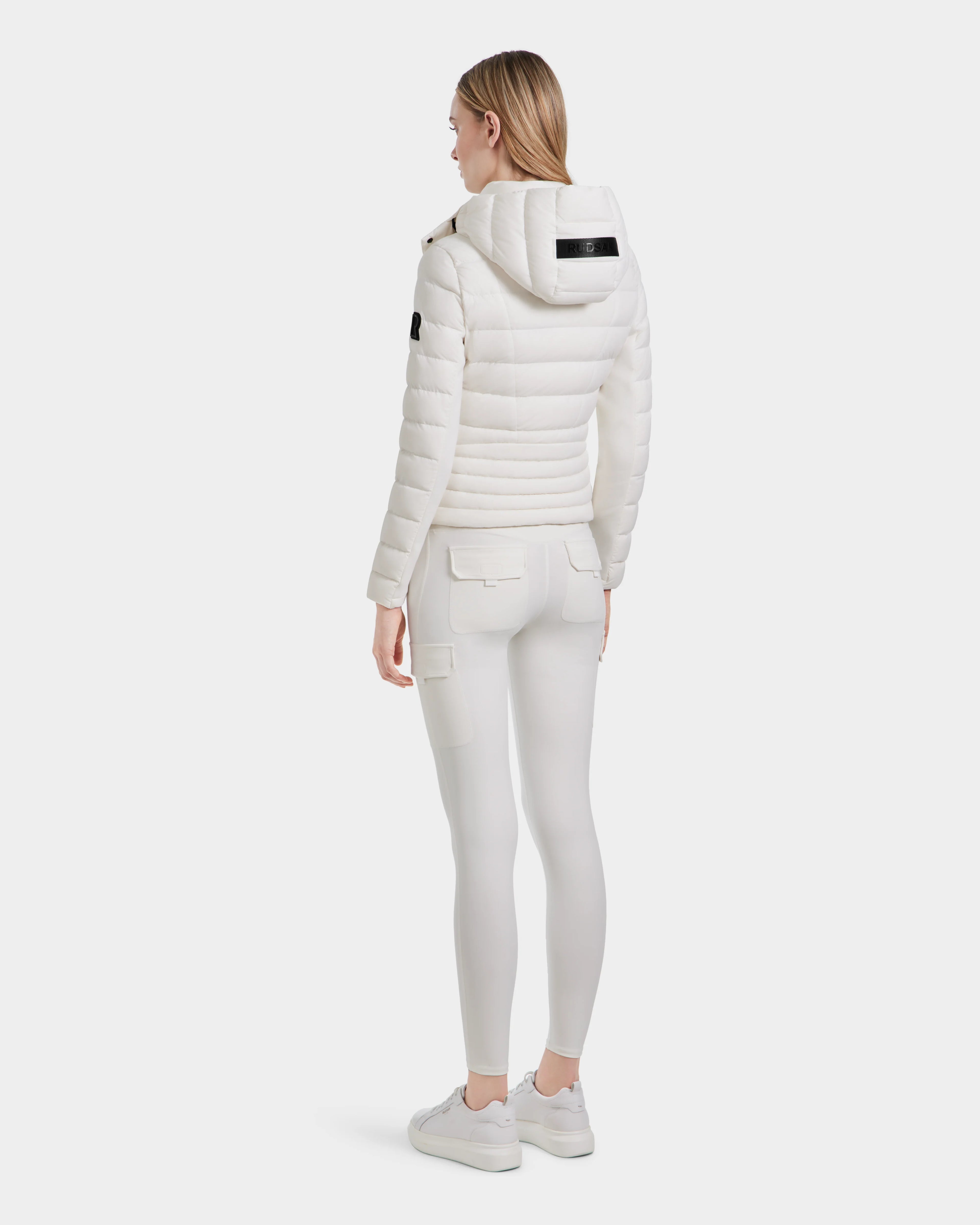 A woman in MELISSA - 8124031 Cotton White pants by Rudsak and a women’s lightweight down puffer, crafted from RDS certified down.