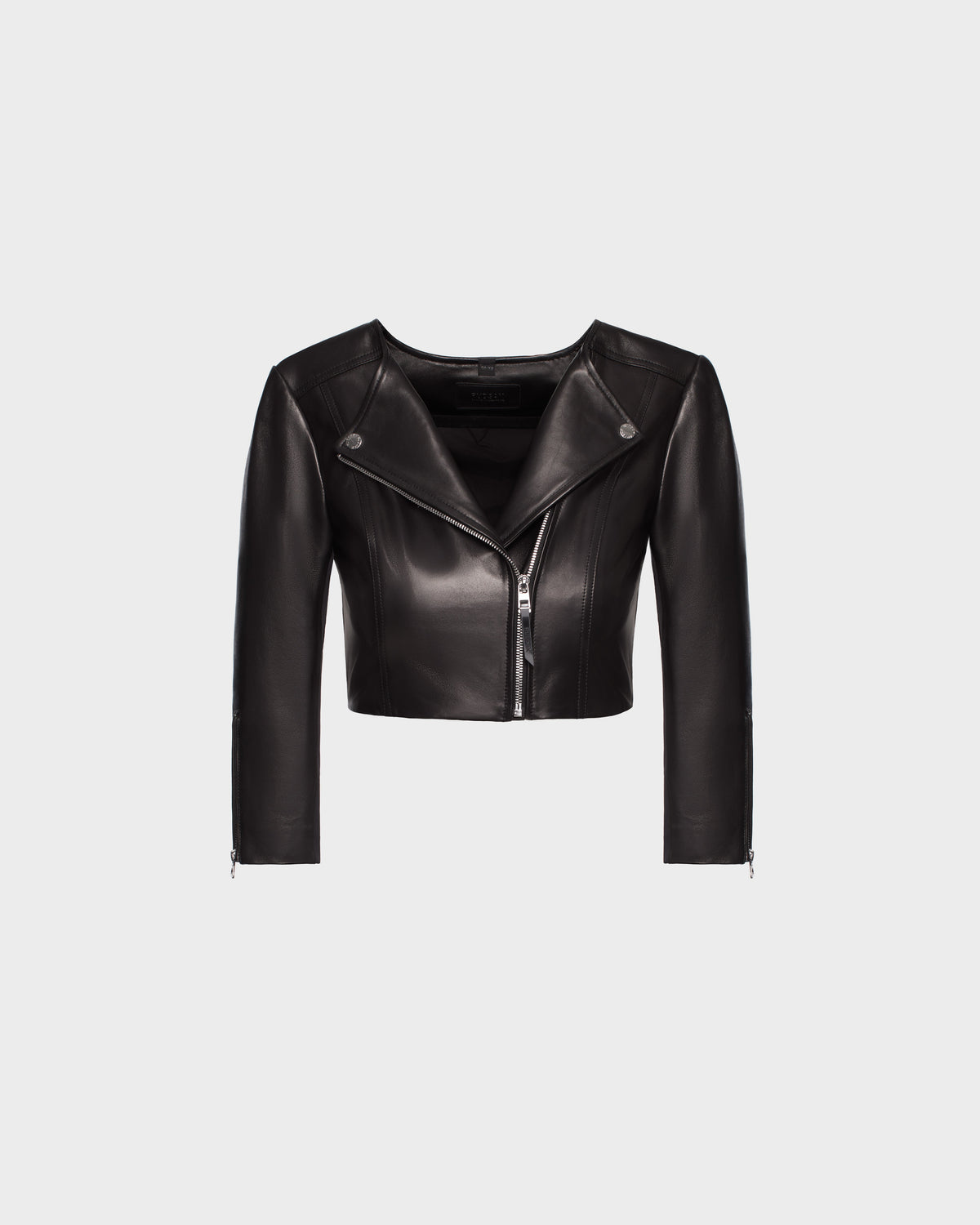 The WINNI - 8124053 Black by Rudsak is a fitted black cropped leather biker jacket with a front zipper, asymmetrical neckline, and long sleeves, shown on a plain light gray background.