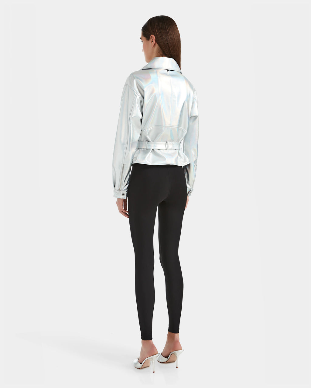 A woman faces away, wearing the Rudsak ARIELLE - 8124052 Iridescent Cotton White jacket, black leggings, and white high heels against a plain white background.