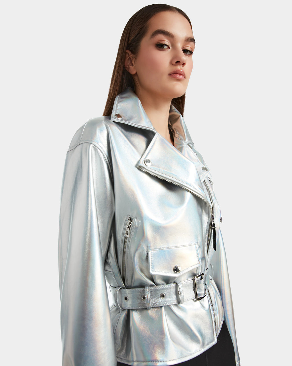 A woman with straight brown hair stands confidently against a light background, wearing the Rudsak ARIELLE - 8124052 jacket in iridescent cotton white.