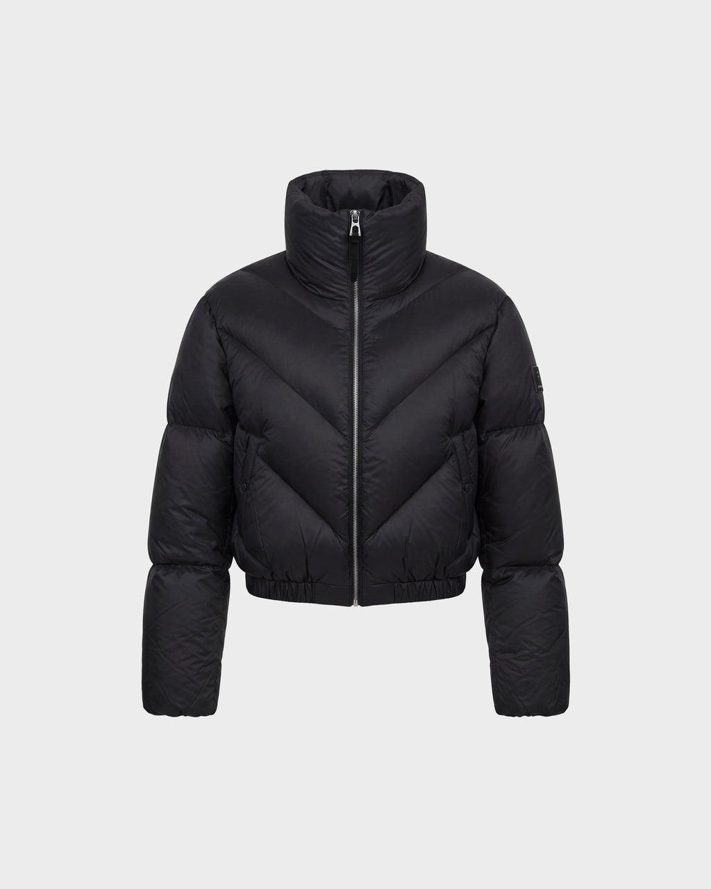 A black, cropped puffer jacket by Rudsak (ANSLIE - 8126986 Black) with a high collar and front zipper, displayed on a plain light gray background. The jacket features horizontal and diagonal quilted patterns.